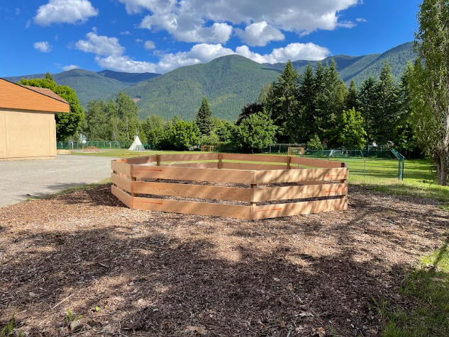 A wooden circular fence in a yard

Description automatically generated