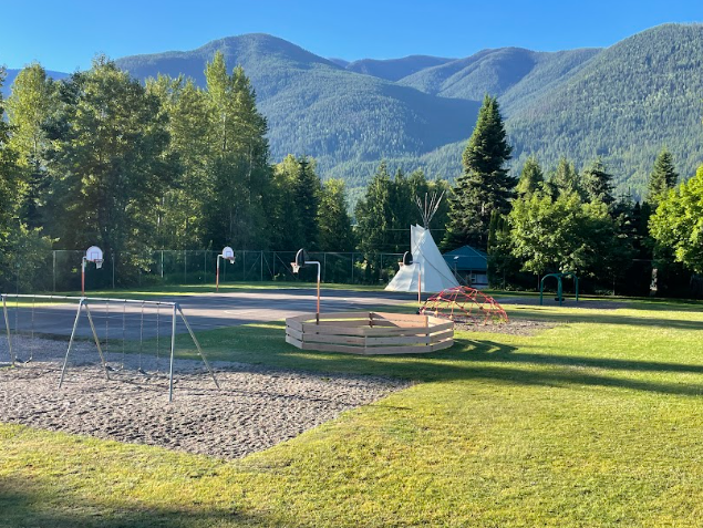A playground with a playground and a teepee in the background

Description automatically generated
