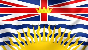 B.C. Day The B.C. provincial flag showing the union jack at the top, at the centre of which is the crown of King Edward and the bottom of the flag shows wavy blue lines representing the Pacific ocean with a yellow setting sun at the bottom.